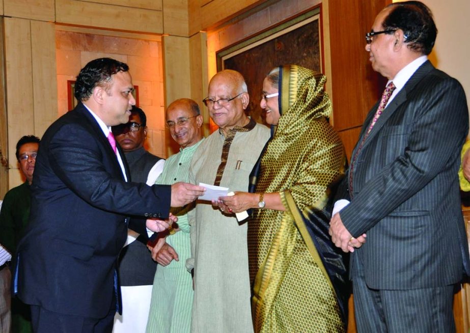 Vice Chairman of NCC Bank A. S. M. Mainuddin Monem handing over a cheque worth Tk. 50 lac to Prime Minister Sheikh Hasina for the ICC T20 World Cup 2014 and Lakho Konthe Sonar Bangla Fund at a simple ceremony at Ganabhaban recently. Finance Minister AMA M