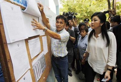 Thai Prime Minister Yingluck Shinawatra Â® checks a list of voters' names before voting at a polling station in Bangkok on Sunday.