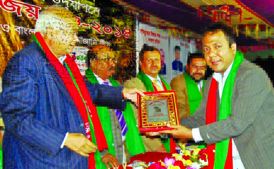 Housing and Public Works Minister Engineer Mosharraf Hossain handing over citation crest to MA Hasan Joy for his contribution in social services at Suhrawardy Udyan in the city on Tuesday.