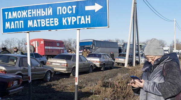 A woman looks at her mobile phone near a queue of cars as they cross the Russian border check point near the town of Uspenka, on Saturday.