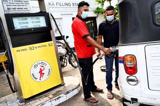 Fuel is being put into a bus in Sree lanka hurriedly.