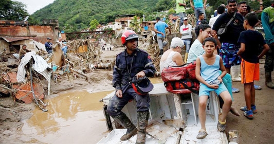 A rescue member and locals rest following a landslide due to heavy rains, in Las Tejerias, Aragua state, Venezuela.