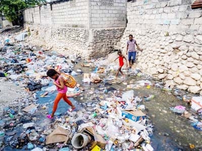 Two girls leap over a stream filled with trash in Port-au-Prince, Haiti on Friday.