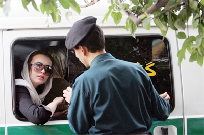 File photo: An Iranian policeman speaks with a woman in a police car after she was arrested because of her 'inappropriate' clothes.