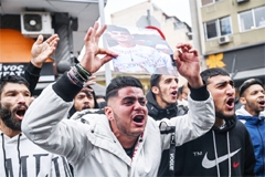 Relatives and other protesters from the Roma community hold up photos of an injured 16-year-old and call for justice in Athens, Greece on Friday.