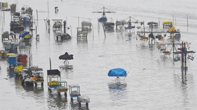 People stand in a flooded area of Marina beach in Chennai on December 10, 2022, following the cyclonic storm Mandous.
