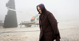 An old woman walks at the Sofiyska square as municipal workers install a Christmas tree during a heavy fog, amid Russia's invasion of Ukraine, in Kyiv, Ukraine on Saturday.