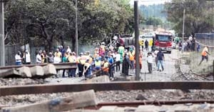People gather near a burnt-out truck at the entrance of the damaged bridge where a gas tanker exploded in Boksburg near Johannesburg, South Africa on Saturday.
