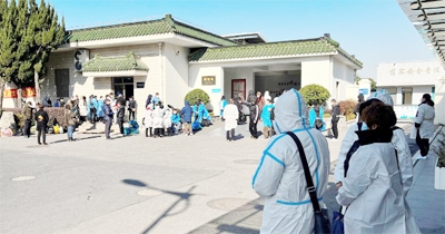 File photo: People wearing personal protective equipment (PPE) stand outside a funeral home, as coronavirus disease outbreak continues, in Shanghai, China December 24, 2022.