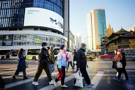 People wearing protective masks cross a street as China returns to work despite continuing coronavirus disease (Covid-19) outbreaks in Shanghai, China on Tuesday.