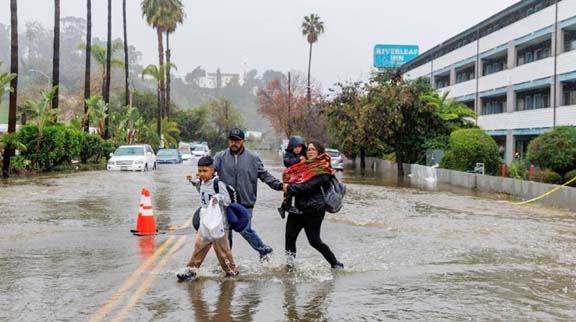 People deal with a flooded street as they check out of a hotel in San Diego, California, US on Monday. Agency photo